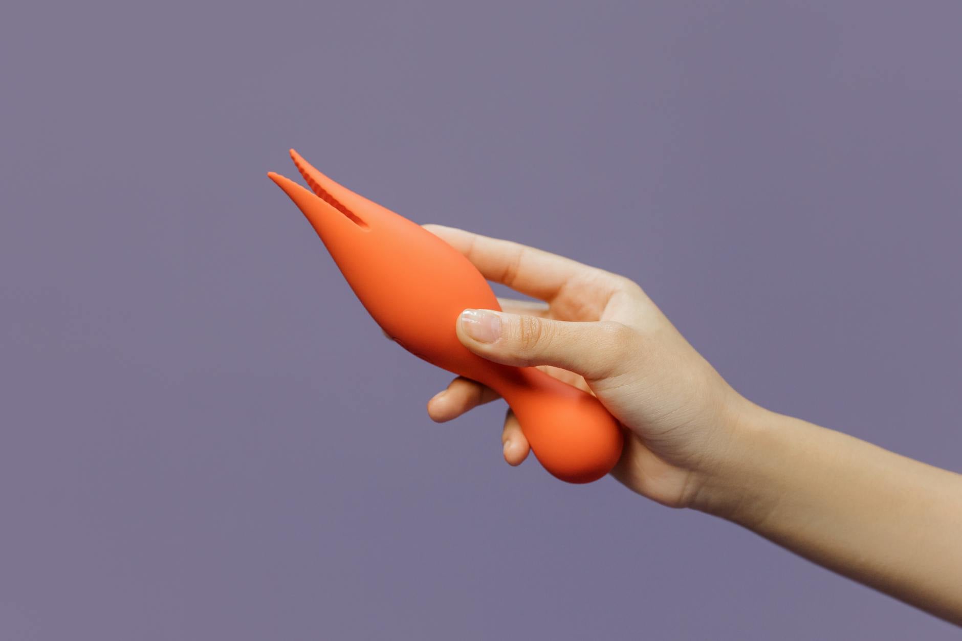 Hand holding a lemon vibrator against a minimalist purple backdrop