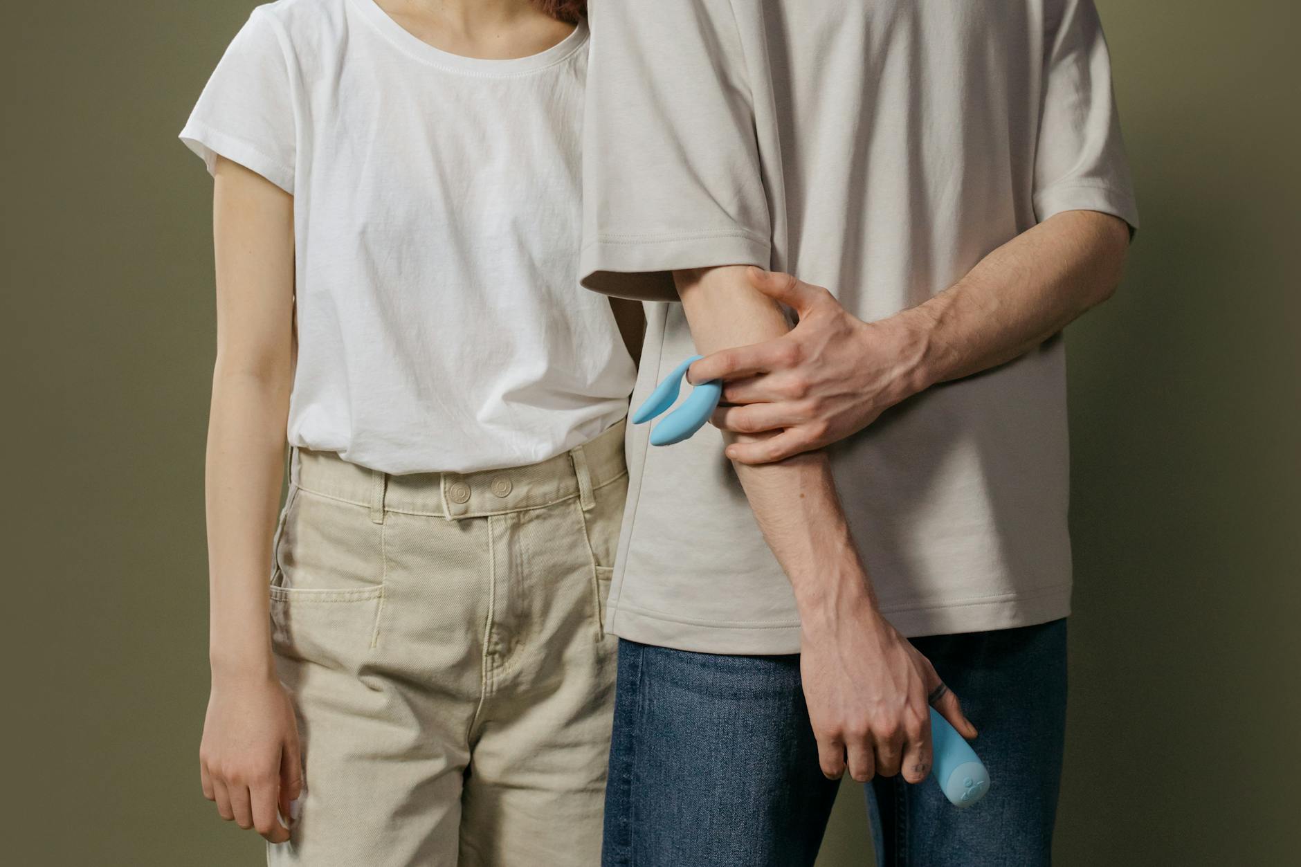 A young couple standing together indoors, having an intimate conversation about introducing toys into their relationship.