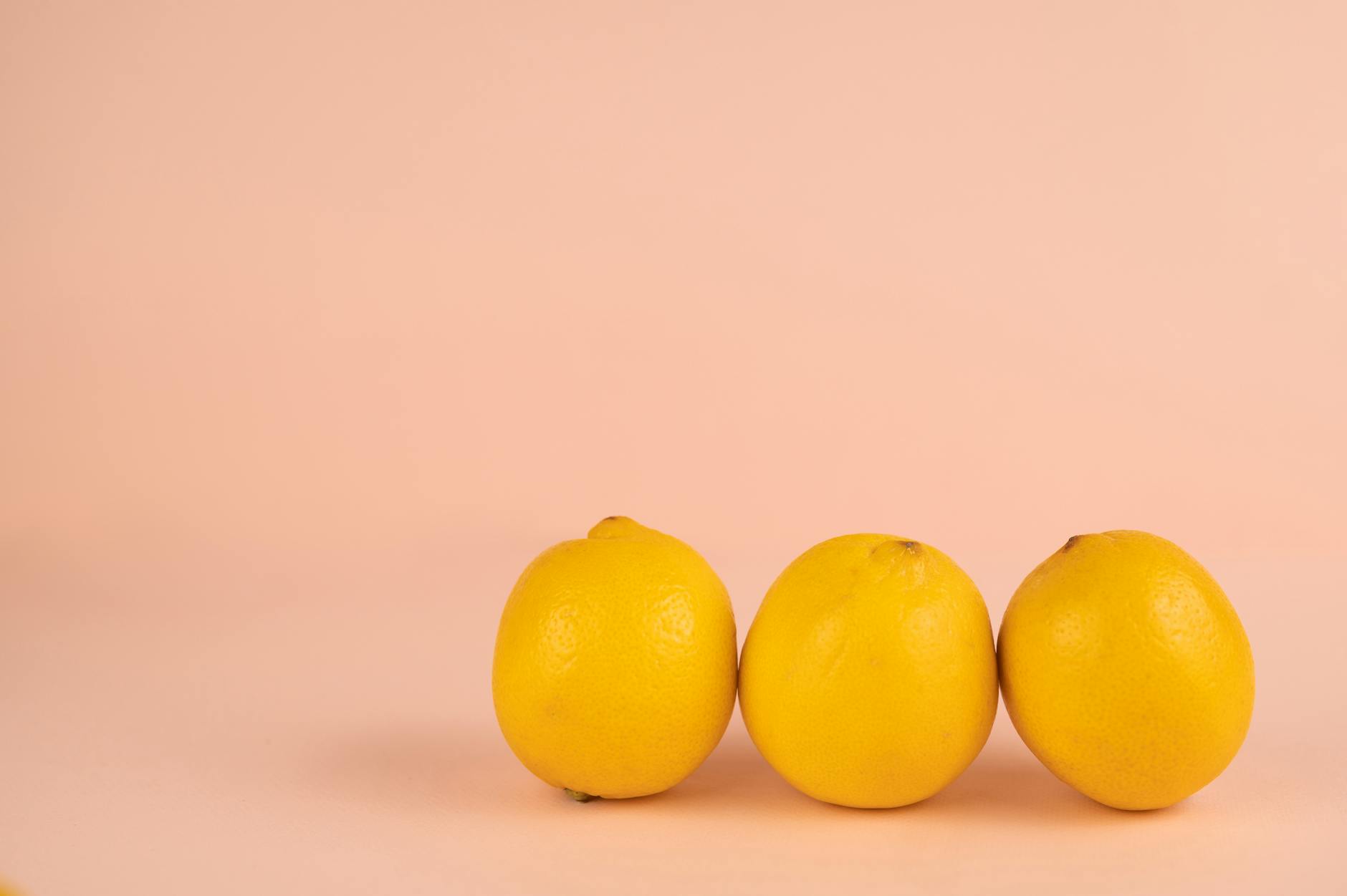 Rangée de citrons frais avec des pédoncules sur un fond pastel coloré